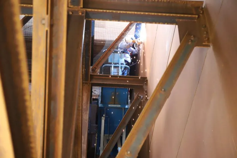 Welder constructing a baghouse dust collector