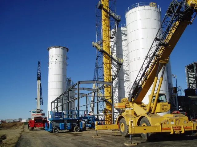 Job site construction showing installation of metal supports for the baghouse dust collector and mechanical bucket elevator for silo.